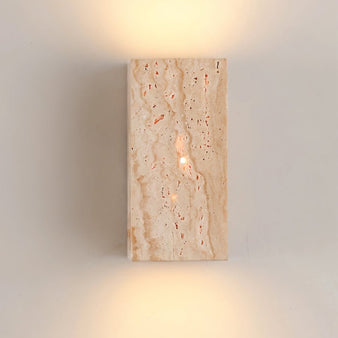 "A modern, rectangular wall lamp made of yellow travertine, emitting a soft, ambient glow upwards and downwards on a neutral wall."