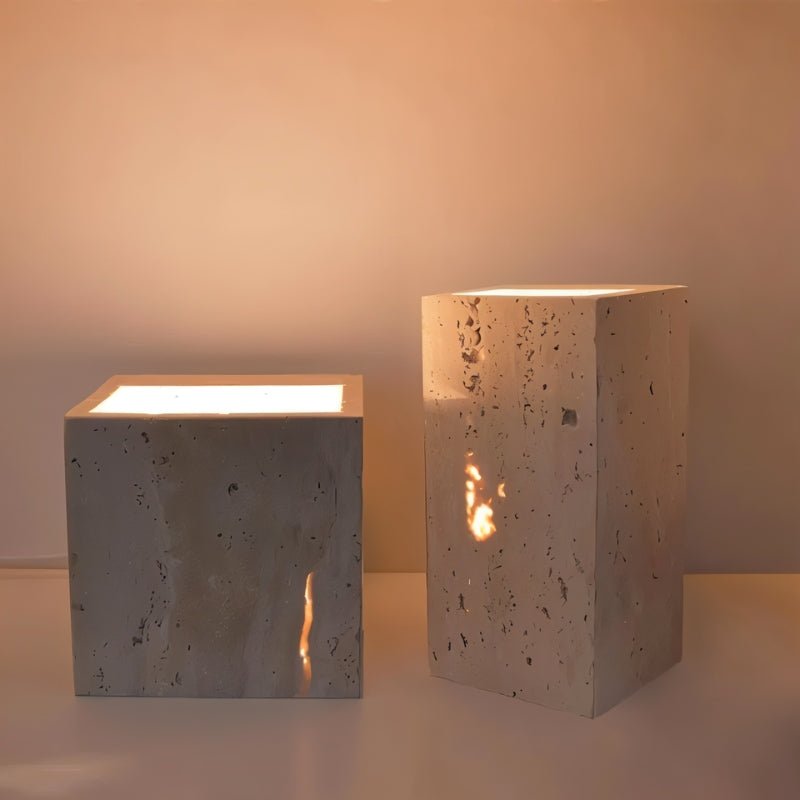 "A pair of modern, cube-shaped wall lamps made of yellow travertine, placed on a white surface, emitting a soft, ambient glow."