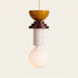 Pixie Pendant Light featuring a glossy mustard bowl top, stacked wooden base, and frosted globe, set against a plain white ba