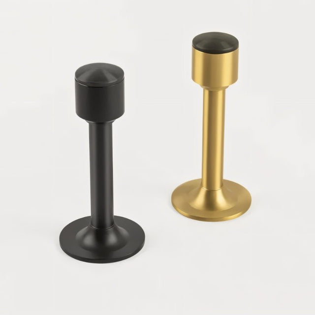 "Sculpted brass door stops with sleek, tapered silhouettes, polished finishes, wide stable bases, and magnetic holds in black and gold, designed to prevent wall damage."