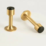 "Two sculpted brass door stops with sleek, tapered silhouettes, polished finishes, wide stable bases, and magnetic holds, designed to prevent wall damage."