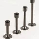 "Sculpted brass door stops with sleek, tapered silhouettes, polished finishes, wide stable bases, and magnetic holds in various modern finishes, designed to prevent wall damage."