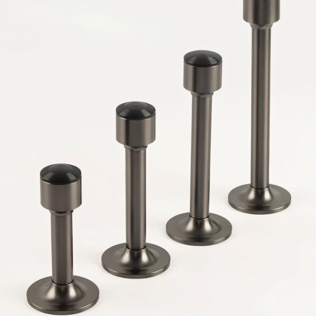 "Sculpted brass door stops with sleek, tapered silhouettes, polished finishes, wide stable bases, and magnetic holds in various modern finishes, designed to prevent wall damage."