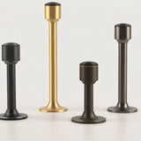 "Sculpted brass door stops with sleek, tapered silhouettes, polished finishes, wide stable bases, and magnetic holds in various modern finishes, designed to prevent wall damage."