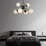 "Starburst chandelier with iron arms and textured acrylic diffusers, hanging above a contemporary bed."