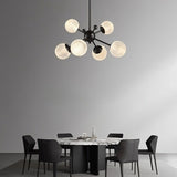 "Starburst chandelier with iron arms and textured acrylic diffusers, hanging above a dining table with chairs."