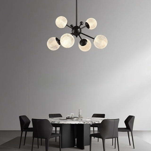 "Starburst chandelier with iron arms and textured acrylic diffusers, hanging above a dining table with chairs."
