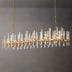 Prizma linear chandelier with gold finish and glass accents, suspended against a plain gray background, measures approximatel