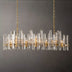 Prizma linear chandelier with gold finish and clear glass prisms, hanging against a plain dark gray background, 36 inches lon