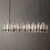 Prizma linear chandelier with glass and metal finish, suspended against a plain gray background, approximately 36 inches long