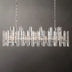 Prizma Linear Chandelier with clear glass prisms and candle-style lights, hanging against a plain gray background.