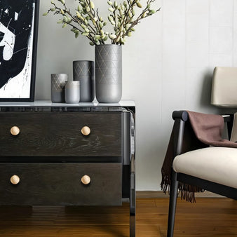 "Dome-shaped brass knobs with flared bases on a dark wood dresser in a modern living room."