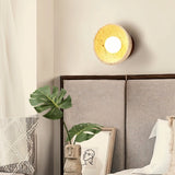 "Modern travertine wall lamp with a circular wooden backplate in a minimalist bedroom setting."