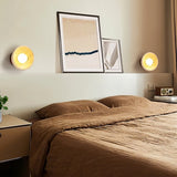  "Pair of travertine wall lamps with circular wooden backplates, mounted on a bedroom wall to provide soft, ambient lighting."