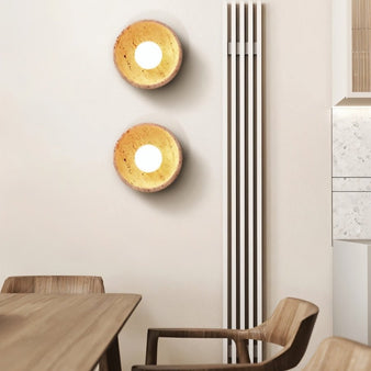 "Pair of modern travertine wall lamps with integrated lighting, adding warmth and texture to a dining room."