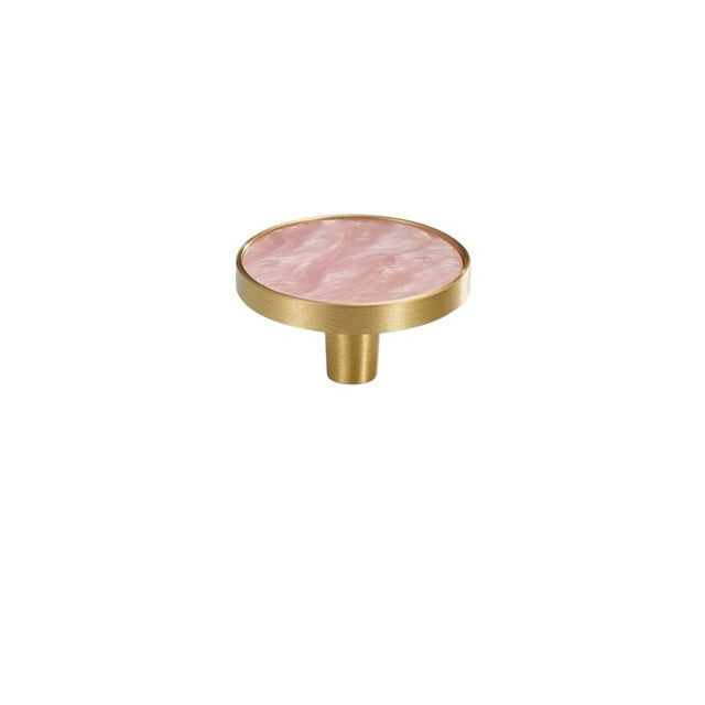 "Top view of a round brass cabinet knob with a pink shell inlay, isolated on a white background."