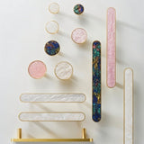 "Brass knobs and pull bars with intricate shell inlays, adding a touch of modern elegance to cabinets and drawers."