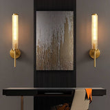 "A pair of modern brass wall lamps with textured glass shades flanking a framed artwork."