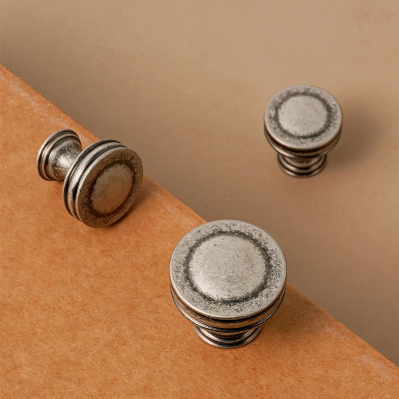 "Close-up of vintage-inspired layered brass knobs with a distressed finish, showcasing their texture and detail."