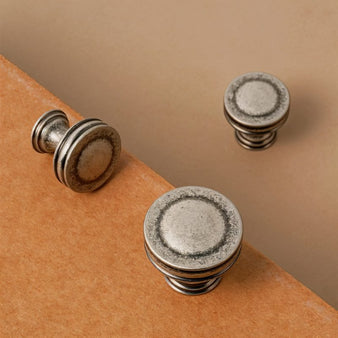 "Close-up of vintage-inspired layered brass knobs with a distressed finish, showcasing their texture and detail."