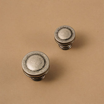 "Vintage-inspired layered brass knobs with a distressed finish for cabinets and drawers."