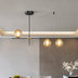 Modern black metal chandelier with amber glass globes suspended over a minimalist dining area with white and gray walls.