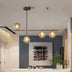 Modern pendant chandelier with black metal frame and amber glass globes hanging above a kitchen island.