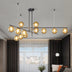 Modern chandelier with amber glass globes and black metal frame suspended in contemporary living room with city view.