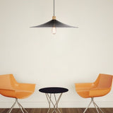 "Raida pendant light with a sleek black conical design, hanging over a modern living room setup featuring orange chairs and a black table, offering a stylish and inviting atmosphere."