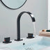 Black arc bathroom faucet with dual handles installed on white sink basin with running water.