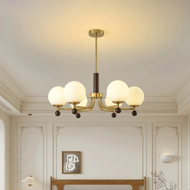 "Ralie chandelier with iron, wood, and glass globes hanging in a bedroom above a wooden headboard."