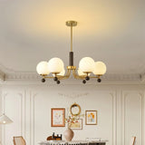 "Ralie chandelier with iron, wood, and glass globes hanging in a dining room above a round table."