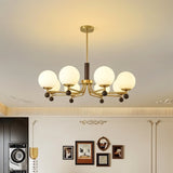 "Ralie chandelier with iron, wood, and glass globes hanging in a living room with a laundry machine and framed pictures."