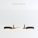 Modern three-light pendant fixture with wood accents and black and white drum shades on white background.