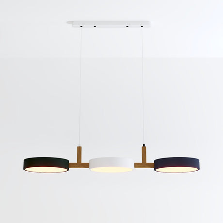 Modern three-light pendant fixture with wood accents and black and white drum shades on white background.