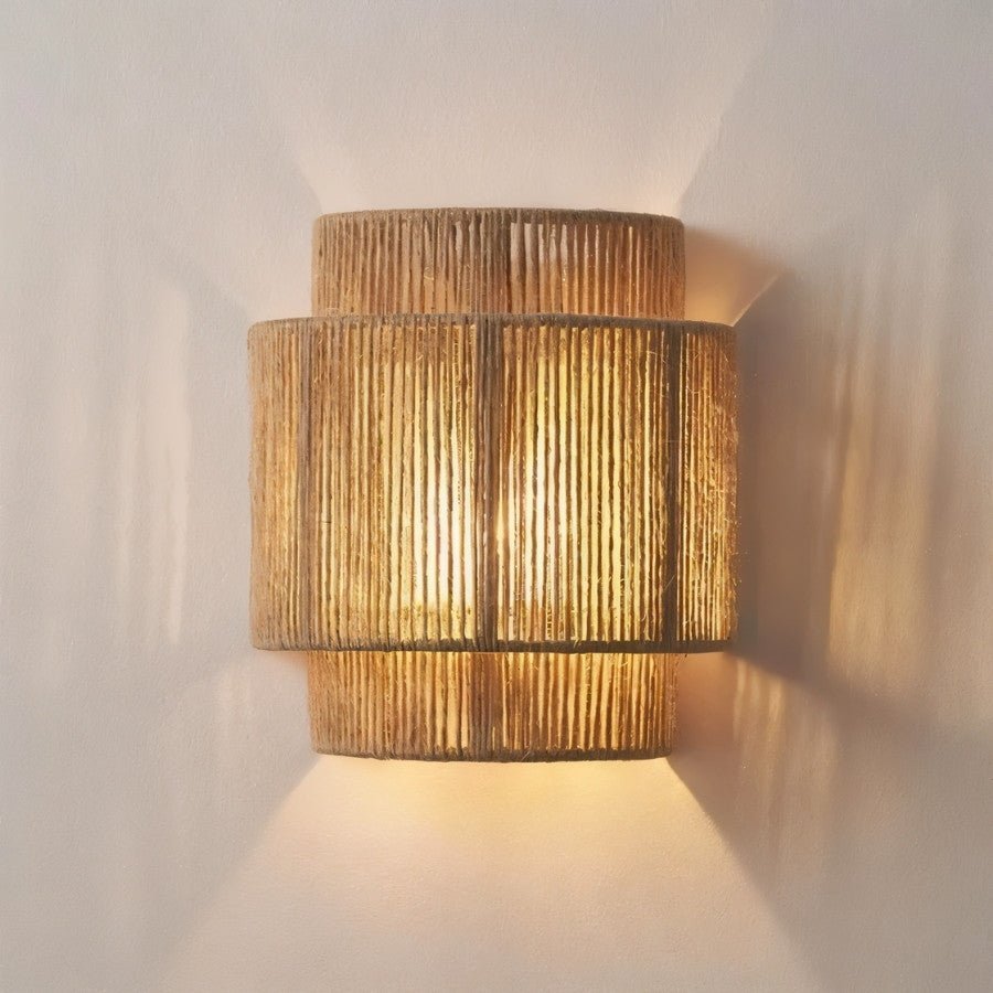 "Close-up of a layered cylindrical wall lamp made of bamboo, rattan, and hemp rope, showcasing its intricate weave and warm light."