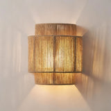 "Close-up of a layered cylindrical wall lamp made of bamboo, rattan, and hemp rope, showcasing its intricate weave and warm light."