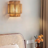 "A rustic bedroom featuring a layered bamboo and rattan wall lamp with hemp rope detailing, providing warm, patterned lighting."