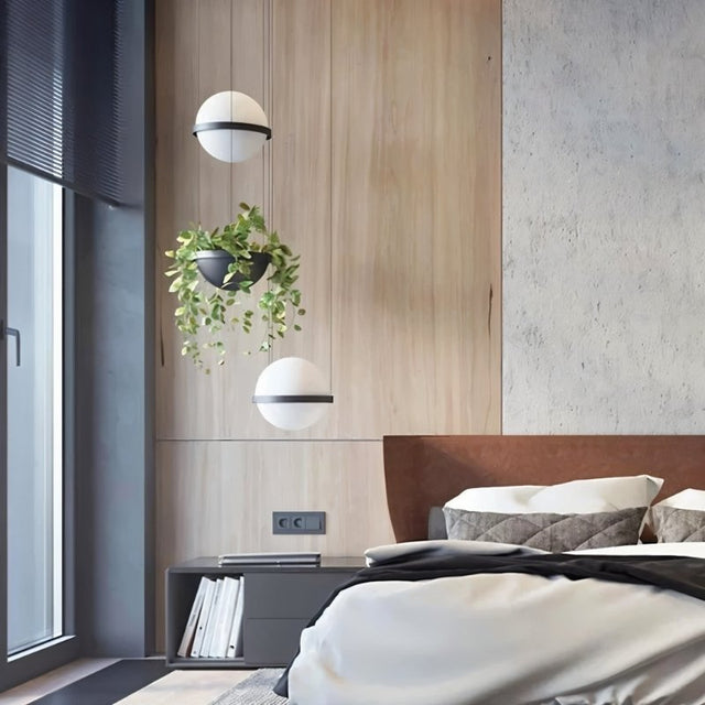 "Modern pendant lights with spherical frosted glass diffusers and iron bands, combined with hanging planters in a contemporary bedroom."