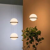 "Grouping of modern pendant lights with spherical frosted glass diffusers and iron bands in a contemporary living room."