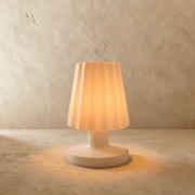 White tapered table lamp on wooden outdoor table with sea view, dusk sky background, lifestyle setting