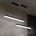 Two black linear pendant lights with white LED panels hang from a concrete ceiling in a modern interior space.