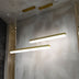 Two brass pendant lights with white diffusers hang in a modern interior with textured gray walls.