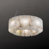 Alabaster drum pendant light with veined cream panels suspended by metal wires against a dark background.
