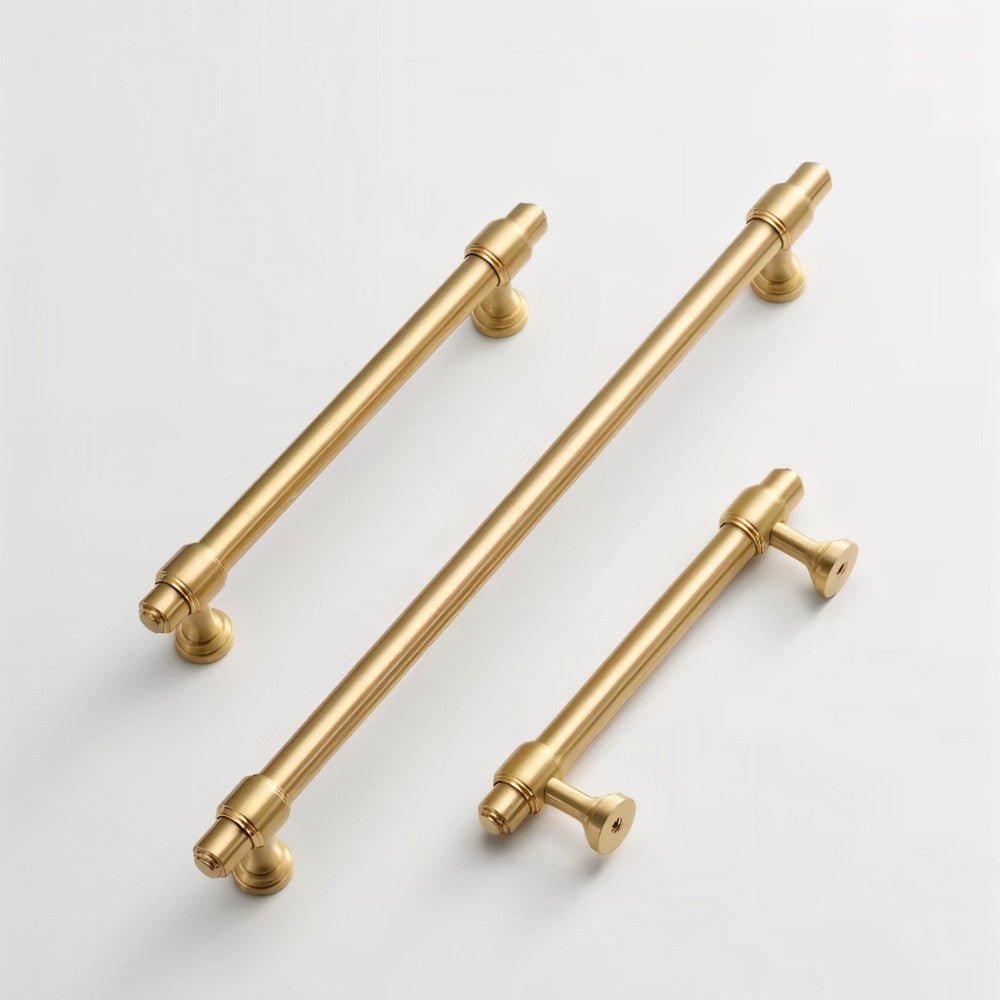 "Three solid brass pull bar handles with a cylindrical design and machined details, arranged diagonally on a light background."