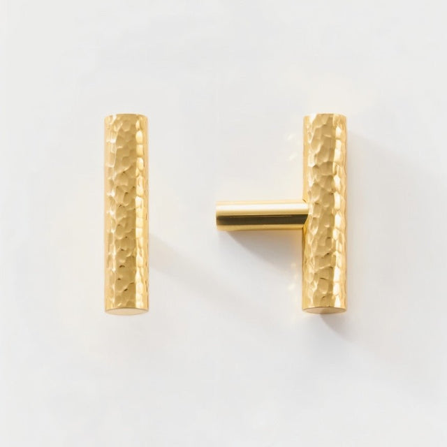 "Set of hammered brass knobs and matching pull bar, featuring a textured, artisanal design suitable for cabinetry and doors."