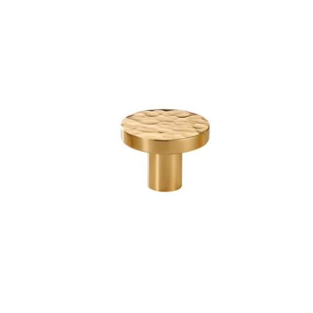 "Close-up of a hammered brass round knob, showcasing its textured, artisanal design."