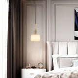 "A modern pendant light with a rounded alabaster shade and brass accents, hanging in a contemporary bedroom, providing a soft, ambient glow."