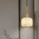 "A modern, minimalist pendant light featuring a rounded alabaster shade with natural veining and brass accents, hanging against a neutral background."