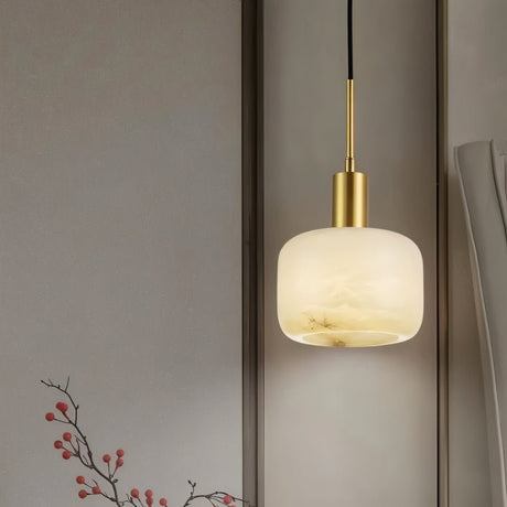"A modern, minimalist pendant light featuring a rounded alabaster shade with natural veining and brass accents, hanging against a neutral background."